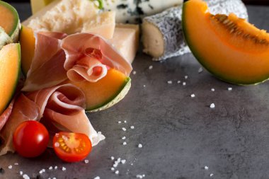 Jambon karışımı. Jambon. Geleneksel İtalyan ve İspanyol Tuzlama, Sigara, Kuru tedavi çanak - jamon Serrano ve prosciutto crudo gri arka plan üzerinde kavun ile dilimlenmiş. Uzay kopyalayın. Portre