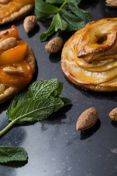Tart with apricot and apple. Traditional french pie with fruits on dark marble background. Decorated almonds and mint leafs. Delicious dessert with copy space closeup — Stock Photo, Image
