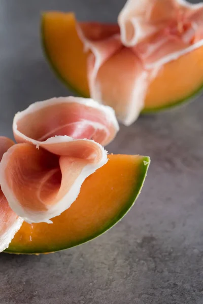 Miscela Jambon. Prosciutto. Salatura tradizionale italiana e spagnola, affumicatura, piatto stagionato a secco - jamon Serrano e prosciutto crudo affettato con melone su fondo grigio. Ricevuto. Primo piano — Foto Stock