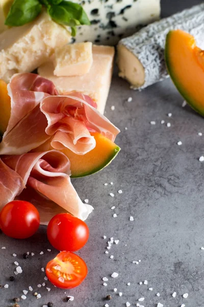 Jambon karışımı. Jambon. Geleneksel İtalyan ve İspanyol Tuzlama, Sigara, Kuru tedavi çanak - jamon Serrano ve prosciutto crudo gri arka plan üzerinde kavun ile dilimlenmiş. Uzay kopyalayın. Portre