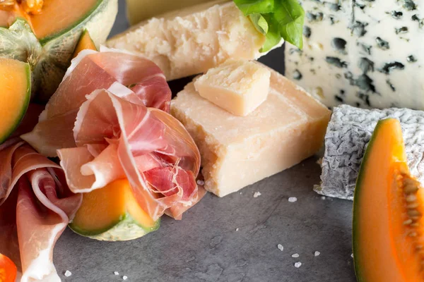 Jambon karışımı. Jambon. Geleneksel İtalyan ve İspanyol Tuzlama, Sigara, Kuru tedavi çanak - jamon Serrano ve prosciutto crudo gri arka plan üzerinde kavun ile dilimlenmiş. Uzay kopyalayın. Portre