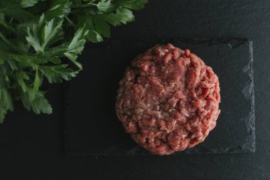 Çiğ biftek. Sığır eti çiğ et baharat, ot ve yumurta sarısı ile kıyılmış. Taze, baharatlı, lezzetli, gurme yemek ile kopya alanı, koyu arka plan üzerinde yakın çekim. Üstten Görünüm.