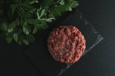 Çiğ biftek. Sığır eti çiğ et baharat, ot ve yumurta sarısı ile kıyılmış. Taze, baharatlı, lezzetli, gurme yemek ile kopya alanı, koyu arka plan üzerinde yakın çekim. Üstten Görünüm.