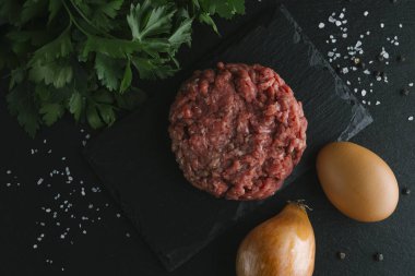 Çiğ biftek. Sığır eti çiğ et baharat, ot ve yumurta sarısı ile kıyılmış. Taze, baharatlı, lezzetli, gurme yemek ile kopya alanı, koyu arka plan üzerinde yakın çekim. Üstten Görünüm.