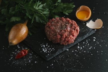 Çiğ biftek. Sığır eti çiğ et baharat, ot ve yumurta sarısı ile kıyılmış. Taze, baharatlı, lezzetli, gurme yemek ile kopya alanı, koyu arka plan üzerinde yakın çekim.
