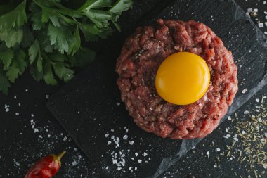 Çiğ biftek. Sığır eti çiğ et baharat, ot ve yumurta sarısı ile kıyılmış. Taze, baharatlı, lezzetli, gurme yemek ile kopya alanı, koyu arka plan üzerinde yakın çekim. Üstten Görünüm.