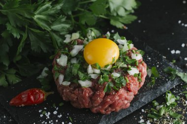 Çiğ biftek. Sığır eti çiğ et baharat, ot ve yumurta sarısı ile kıyılmış. Taze, baharatlı, lezzetli, gurme yemek ile kopya alanı, koyu arka plan üzerinde yakın çekim.