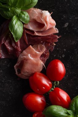 Jambon karışımı. Jambon. Geleneksel İtalyan ve İspanyol Tuzlama, Sigara, otlar ve karanlık taş zemin üzerine domates kuru tedavi çanak - jamon Serrano ve prosciutto crudo dilimlenmiş. Uzay kopyalayın. Portre