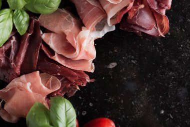 Jambon karışımı. Jambon. Geleneksel İtalyan ve İspanyol Tuzlama, Sigara, otlar ve karanlık taş zemin üzerine domates kuru tedavi çanak - jamon Serrano ve prosciutto crudo dilimlenmiş. Uzay kopyalayın. Portre