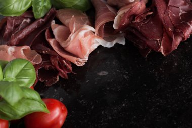 Jambon karışımı. Jambon. Geleneksel İtalyan ve İspanyol Tuzlama, Sigara, otlar ve karanlık taş zemin üzerine domates kuru tedavi çanak - jamon Serrano ve prosciutto crudo dilimlenmiş. Uzay kopyalayın. Portre