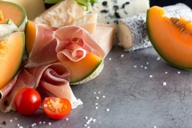 Jambon karışımı. Jambon. Geleneksel İtalyan ve İspanyol Tuzlama, Sigara, Kuru tedavi çanak - jamon Serrano ve prosciutto crudo gri arka plan üzerinde kavun ile dilimlenmiş. Uzay kopyalayın. Portre