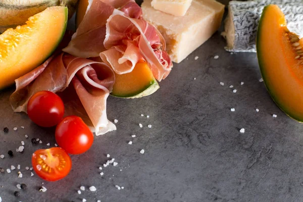 Jambon karışımı. Jambon. Geleneksel İtalyan ve İspanyol Tuzlama, Sigara, Kuru tedavi çanak - jamon Serrano ve prosciutto crudo gri arka plan üzerinde kavun ile dilimlenmiş. Uzay kopyalayın. Portre