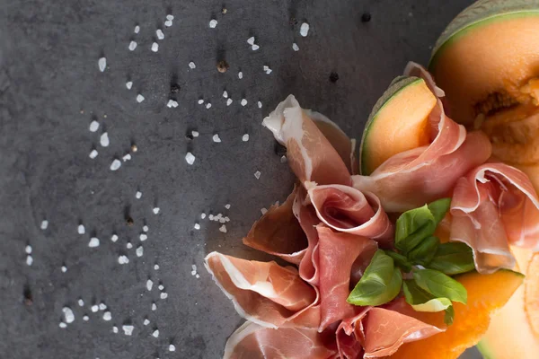 Jambon mix. Ham. Traditional Italian and Spanish salting, smoking, dry-cured dish - jamon Serrano and prosciutto crudo sliced with melon on grey background. Copy space. Closeup — Stock Photo, Image