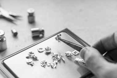 Takı araçları. Takı. Goldsmith işyeri, çalışma alanında açık renkli. El tekne. Atölye. Üretim. Ağırlık pullarla granül metal gümüş ve platin. Portre. Tonda