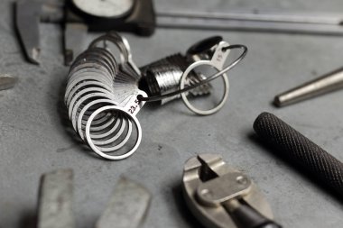 Mücevherat ve mucevherler araçlar kümesi. Takı metal zemin üzerine iş yeri. Parmak boyutlandırma Yüzükler, ışın Pusula, kıskaç, Kerpetenler