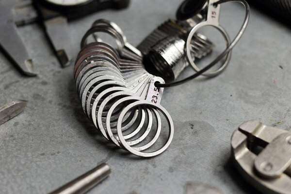 Набор ювелирных изделий. Ювелирные изделия на металлическом фоне. Размеры пальцев для колец, лучевого компаса, клещей, щипцов
