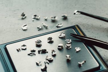 Takı araçları. Takı. Goldsmith işyeri, çalışma alanında açık renkli. El tekne. Atölye. Üretim. Ağırlık pullarla granül metal gümüş ve platin. Portre. Tonda