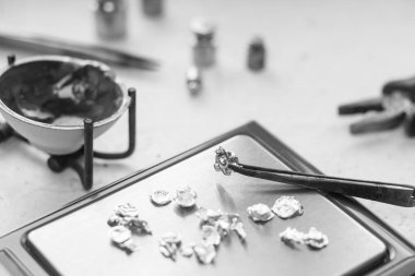 Takı araçları. Takı. Goldsmith işyeri, çalışma alanında açık renkli. El tekne. Atölye. Üretim. Ağırlık pullarla granül metal gümüş ve platin. Portre. Tonda