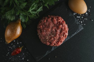 Çiğ biftek. Sığır eti çiğ et baharat, ot ve yumurta sarısı ile kıyılmış. Taze, baharatlı, lezzetli, gurme yemek ile kopya alanı, koyu arka plan üzerinde yakın çekim. Üstten Görünüm.