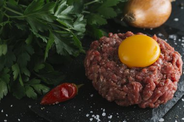 Çiğ biftek. Sığır eti çiğ et baharat, ot ve yumurta sarısı ile kıyılmış. Taze, baharatlı, lezzetli, gurme yemek ile kopya alanı, koyu arka plan üzerinde yakın çekim.