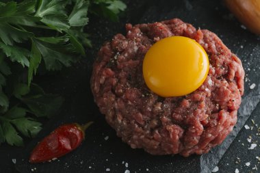 Çiğ biftek. Sığır eti çiğ et baharat, ot ve yumurta sarısı ile kıyılmış. Taze, baharatlı, lezzetli, gurme yemek ile kopya alanı, koyu arka plan üzerinde yakın çekim.