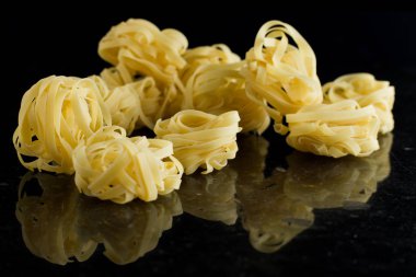 Makarna Tagliatelle mermer masaya düzenlenmiştir. Ham closeup arka plan. Geleneksel İtalyan mutfağı yemek için lezzetli kuru pişmemiş madde. Üstten Görünüm. Kopya alanı