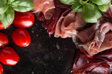 Jambon karışımı. Jambon. Geleneksel İtalyan ve İspanyol Tuzlama, Sigara, otlar ve karanlık taş zemin üzerine domates kuru tedavi çanak - jamon Serrano ve prosciutto crudo dilimlenmiş. Uzay kopyalayın. Portre