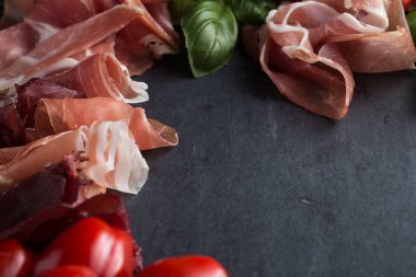 Jambon karışımı. Jambon. Geleneksel İtalyan ve İspanyol Tuzlama, Sigara, otlar ve karanlık taş zemin üzerine domates kuru tedavi çanak - jamon Serrano ve prosciutto crudo dilimlenmiş. Uzay kopyalayın. Portre