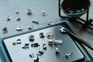 Takı araçları. Takı. Goldsmith işyeri, çalışma alanında açık renkli. El tekne. Atölye. Üretim. Ağırlık pullarla granül metal gümüş ve platin. Portre. Tonda