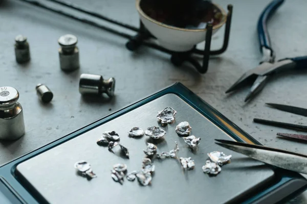 Takı araçları. Takı. Goldsmith işyeri, çalışma alanında açık renkli. El tekne. Atölye. Üretim. Ağırlık pullarla granül metal gümüş ve platin. Portre. Tonda