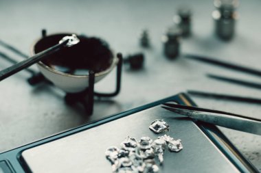 Takı araçları. Takı. Goldsmith işyeri, çalışma alanında açık renkli. El tekne. Atölye. Üretim. Ağırlık pullarla granül metal gümüş ve platin. Portre. Tonda