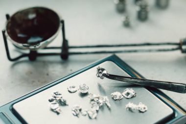 Takı araçları. Takı. Goldsmith işyeri, çalışma alanında açık renkli. El tekne. Atölye. Üretim. Ağırlık pullarla granül metal gümüş ve platin. Portre. Tonda