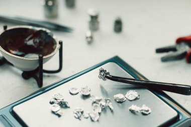 Takı araçları. Takı. Goldsmith işyeri, çalışma alanında açık renkli. El tekne. Atölye. Üretim. Ağırlık pullarla granül metal gümüş ve platin. Portre. Tonda