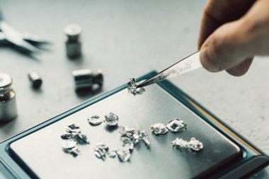 Takı araçları. Takı. Goldsmith işyeri, çalışma alanında açık renkli. El tekne. Atölye. Üretim. Ağırlık pullarla granül metal gümüş ve platin. Portre. Tonda