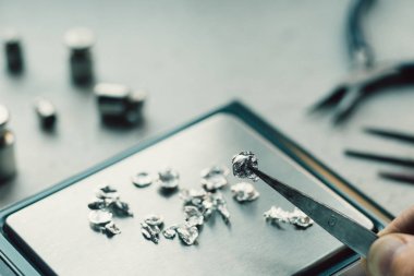 Takı araçları. Takı. Goldsmith işyeri, çalışma alanında açık renkli. El tekne. Atölye. Üretim. Ağırlık pullarla granül metal gümüş ve platin. Portre. Tonda