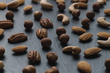 Karışık Kuruyemiş - badem, fındık ve kaju - karanlık arduvaz arka plan kopya alanı ile çeşitli. Üstten Görünüm. Tonda