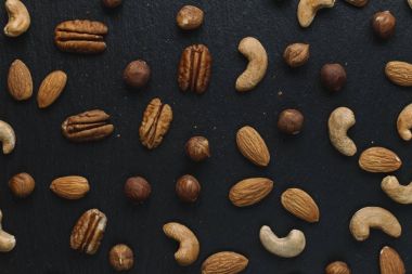 Karışık Kuruyemiş - badem, fındık ve kaju - karanlık arduvaz arka plan kopya alanı ile çeşitli. Üstten Görünüm. Tonda