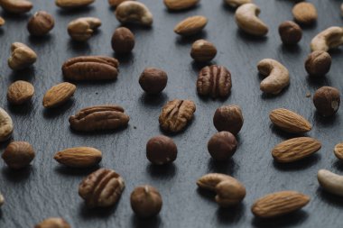 Karışık Kuruyemiş - badem, fındık ve kaju - karanlık arduvaz arka plan kopya alanı ile çeşitli. Üstten Görünüm. Tonda