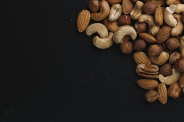 Karışık Kuruyemiş - badem, fındık ve kaju - karanlık arduvaz arka plan kopya alanı ile çeşitli. Üstten Görünüm. Tonda