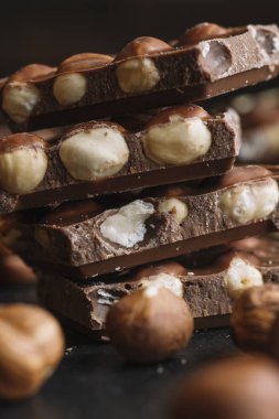 Çikolata parçaları ve fındık kopya alanı ile koyu arka plan üzerinde bar. Çikolata arka plan. Tonda