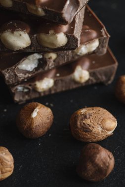 Çikolata parçaları ve fındık kopya alanı ile koyu arka plan üzerinde bar. Çikolata arka plan. Tonda