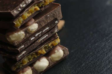 Çikolata parçaları ve fındık kopya alanı ile koyu arka plan üzerinde bar. Çikolata arka plan. Tonda