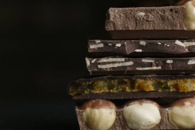 Çikolata parçaları ve fındık kopya alanı ile koyu arka plan üzerinde bar. Çikolata arka plan. Tonda