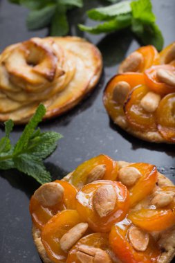 Kayısı ve elma tart. Karanlık mermer zemin üzerine meyve ile geleneksel Fransız pasta. Bir şekilde dekore edilmiş badem ve nane yaprakları. Kopyalama alanı closeup ile lezzetli tatlı