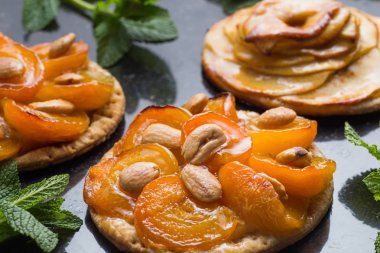Kayısı ve elma tart. Karanlık mermer zemin üzerine meyve ile geleneksel Fransız pasta. Bir şekilde dekore edilmiş badem ve nane yaprakları. Kopyalama alanı closeup ile lezzetli tatlı