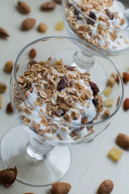 Granola yoğurt, fındık ve açık renkli cam kase meyve ile. Kahvaltı için lezzetli, sağlıklı tatlı tatlı. Mısır gevreği, müsli. Kopya alanı, portre
