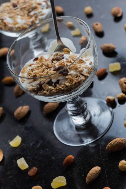 Granola yoğurt, fındık ve koyu arka plan üzerinde cam kase meyve ile. Kahvaltı için lezzetli, sağlıklı tatlı tatlı. Mısır gevreği, müsli. Kopya alanı, portre