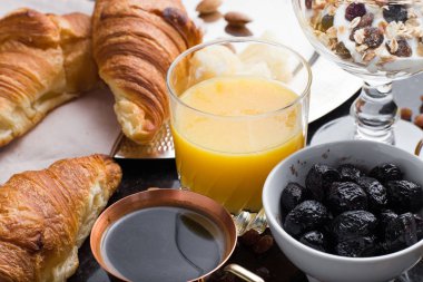 Kahvaltı çeşitli yoğurt, granola, kahve, meyve suyu, kruvasan, zeytin. Meze sabah yemekleri ile karıştırın. Koyu arka plan üzerinde sağlıklı, taze, lezzetli yemek