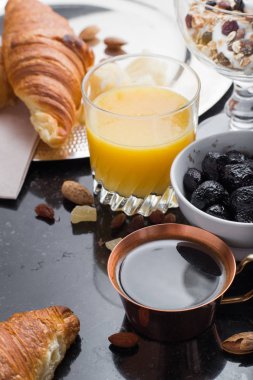 Kahvaltı çeşitli yoğurt, granola, kahve, meyve suyu, kruvasan, zeytin. Meze sabah yemekleri ile karıştırın. Koyu arka plan üzerinde sağlıklı, taze, lezzetli yemek