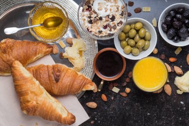 Kahvaltı çeşitli yoğurt, granola, kahve, meyve suyu, kruvasan, zeytin. Meze sabah yemekleri ile karıştırın. Koyu arka plan üzerinde sağlıklı, taze, lezzetli yemek